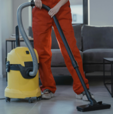Close up of person with orange pants vacuuming the floor