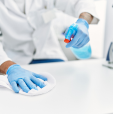 Wearing gloves and scrubbing a white surface